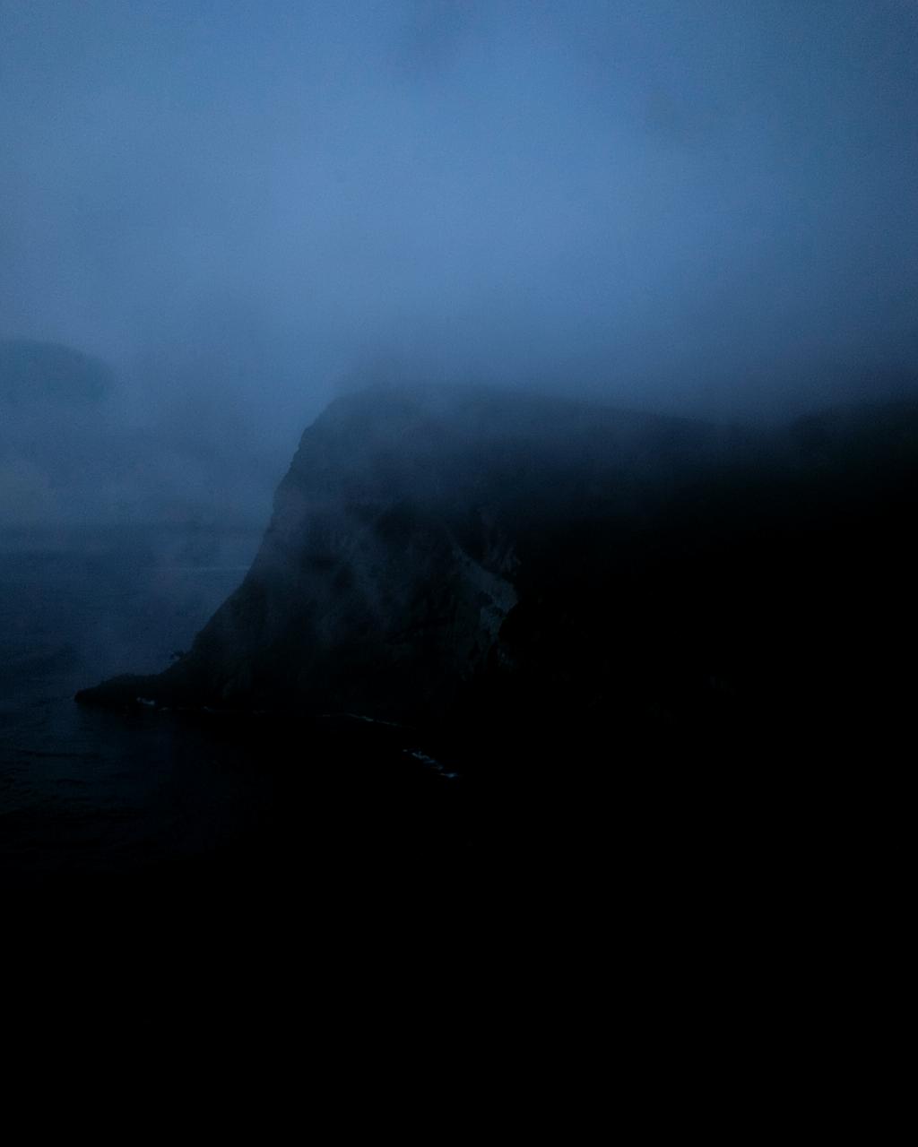 Misty coastal cliff photographed at blue hour
